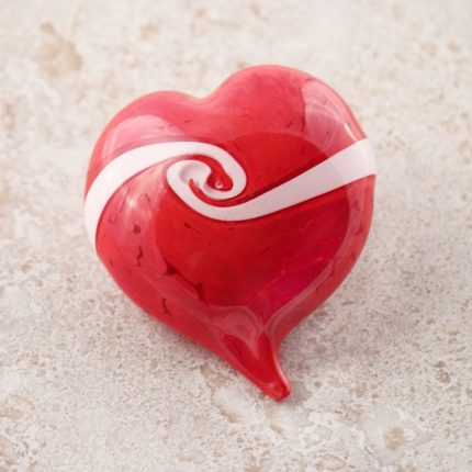 A red heart with a ribbon of white moving from one side to the other with a twist in its center, denoting how two lives come together as one in the heart.