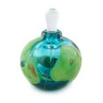 A small perfume bottle made of clear glass in turquoise glass with shards of green glass embedded between layers of clear glass.
