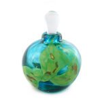 A small perfume bottle made of clear glass in turquoise glass with shards of green glass embedded between layers of clear glass.